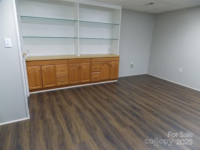 unfurnished living room featuring a paneled ceiling and dark hardwood / wood-style floors