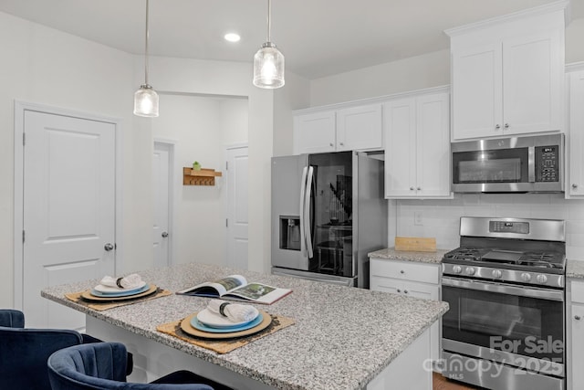 kitchen with tasteful backsplash, white cabinetry, a kitchen island, and appliances with stainless steel finishes