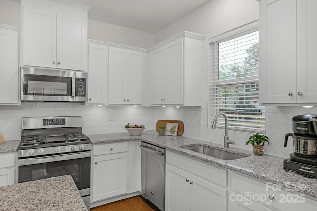 kitchen with white cabinets, backsplash, stainless steel appliances, and sink