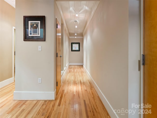 corridor with light hardwood / wood-style floors and ornamental molding