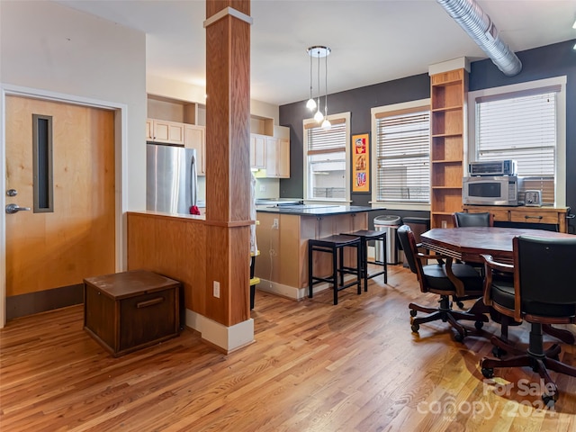 dining room with ornate columns and light hardwood / wood-style floors