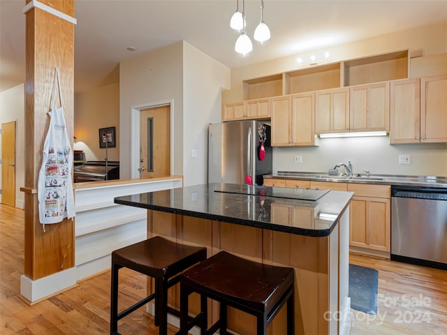 kitchen featuring appliances with stainless steel finishes, a breakfast bar area, a kitchen island, and light hardwood / wood-style flooring