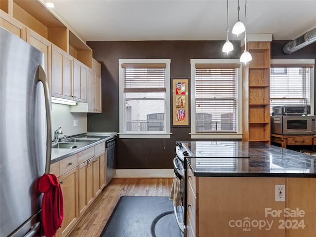 kitchen with stainless steel appliances, a center island, hanging light fixtures, sink, and light hardwood / wood-style flooring