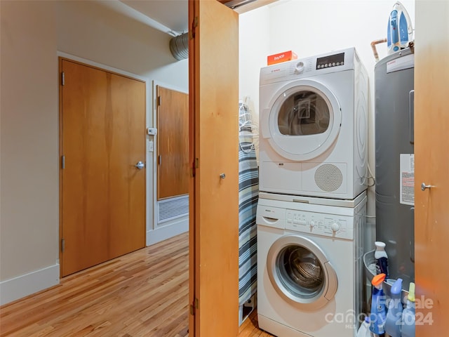 washroom featuring electric water heater, light hardwood / wood-style flooring, and stacked washer and clothes dryer