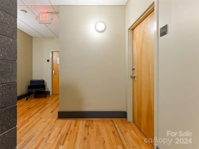 corridor featuring a drop ceiling and hardwood / wood-style floors