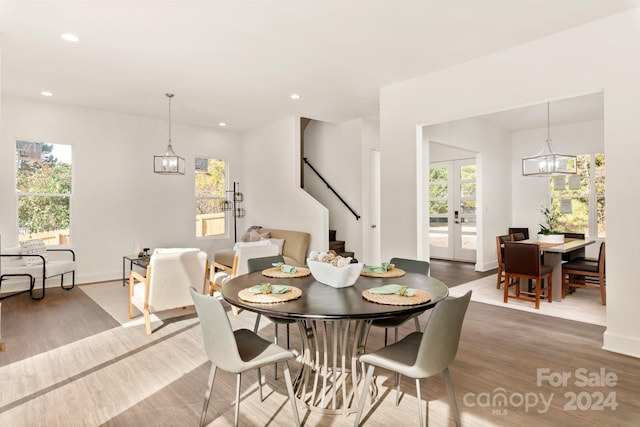 dining space featuring hardwood / wood-style floors, a wealth of natural light, french doors, and a notable chandelier