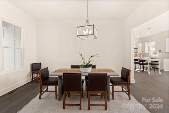 dining area with sink, hardwood / wood-style flooring, and a notable chandelier