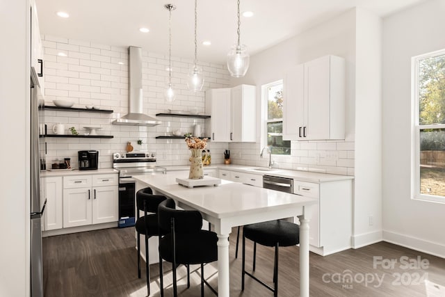 kitchen featuring dark hardwood / wood-style flooring, wall chimney range hood, stainless steel appliances, and white cabinets