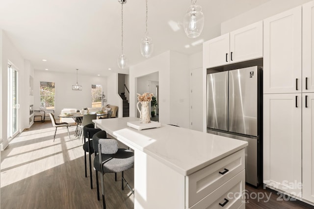 kitchen featuring dark hardwood / wood-style flooring, pendant lighting, stainless steel refrigerator, and white cabinets