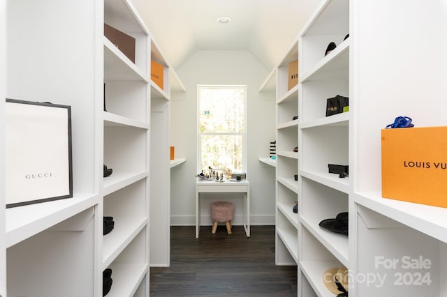 walk in closet with dark wood-type flooring and vaulted ceiling