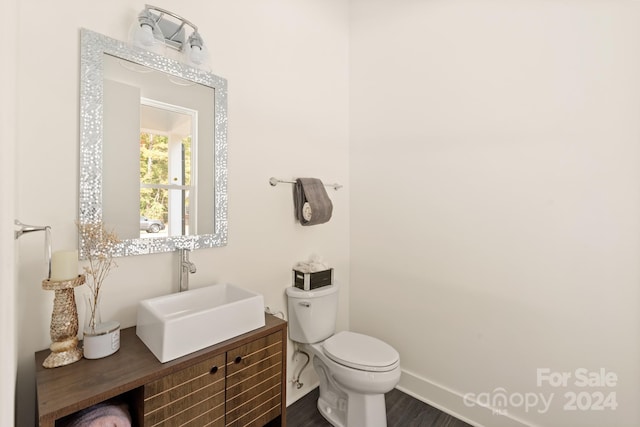 bathroom with wood-type flooring, vanity, and toilet