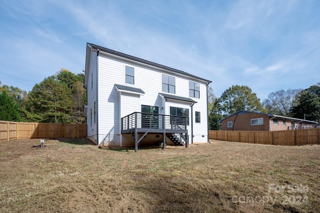 rear view of house with a lawn and a wooden deck