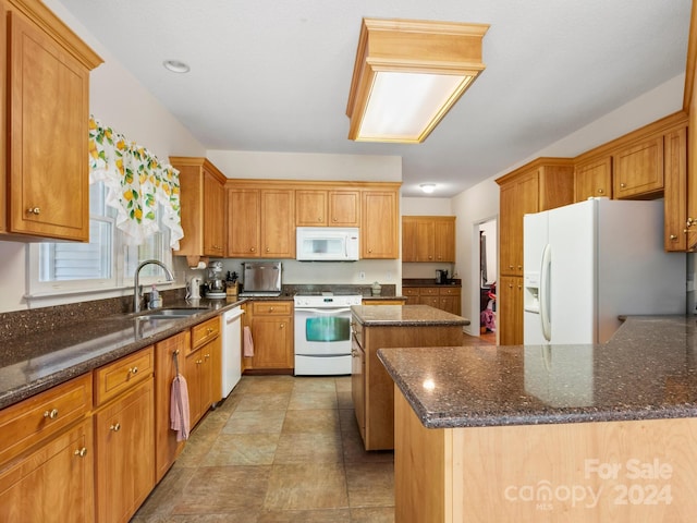 kitchen with dark stone counters, a kitchen island, white appliances, and sink