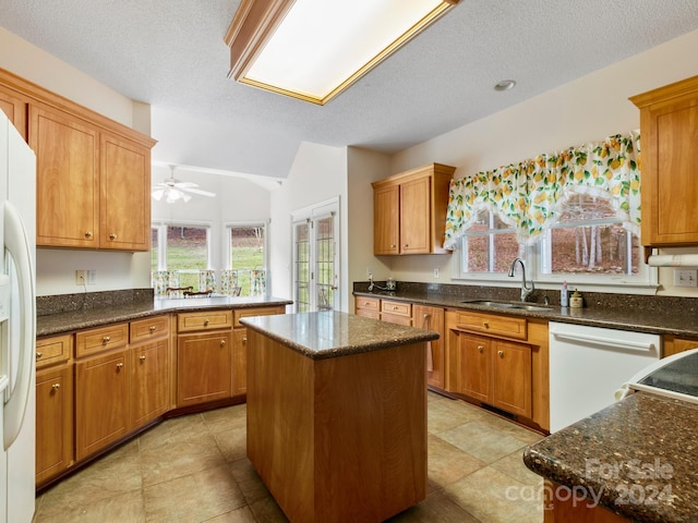 kitchen featuring a textured ceiling, white appliances, sink, and a center island