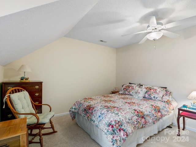 bedroom with ceiling fan, a textured ceiling, light carpet, and vaulted ceiling