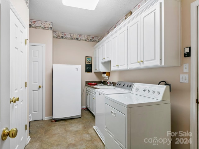 washroom with cabinets, washer and dryer, a textured ceiling, and sink