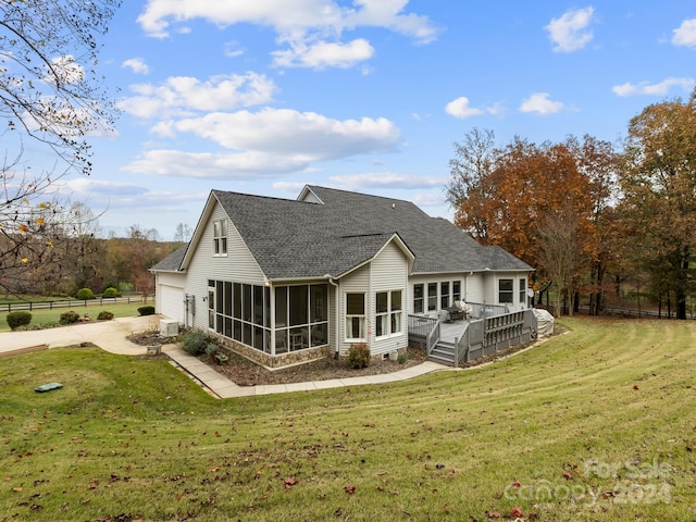 back of property with a lawn, a sunroom, and a wooden deck