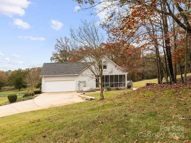 view of front of property featuring a garage, a front lawn, and a sunroom