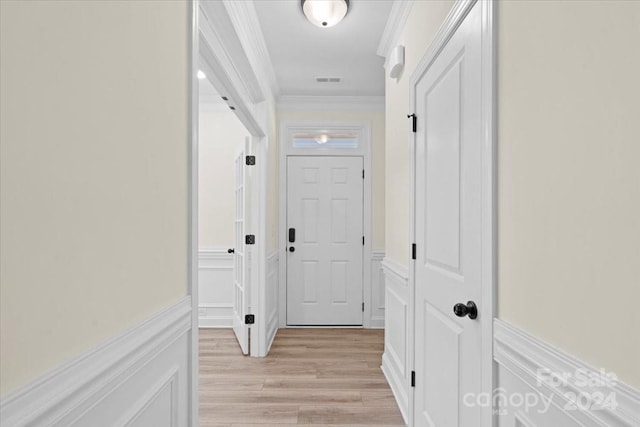 hall with light hardwood / wood-style floors and ornamental molding