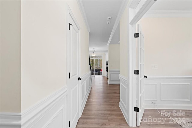 hallway with light hardwood / wood-style flooring and crown molding