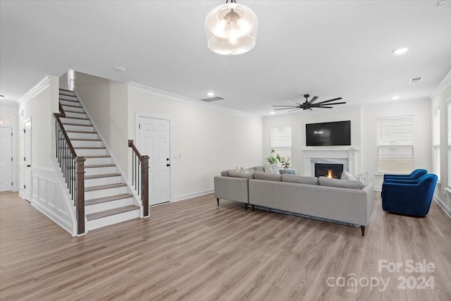 living room with light hardwood / wood-style floors, ceiling fan, and ornamental molding