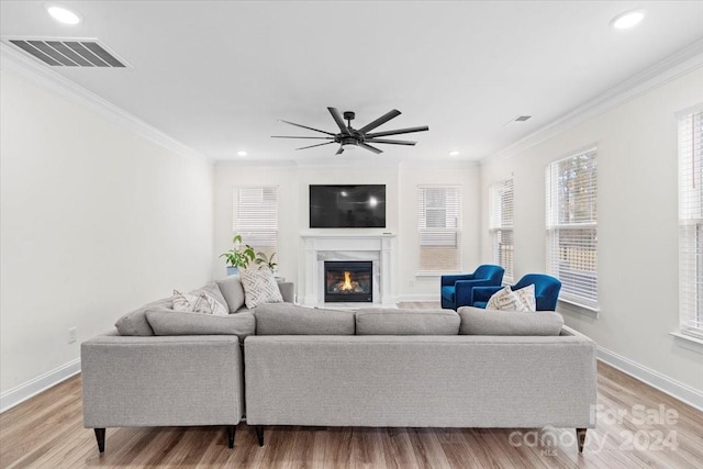 living room featuring light wood-type flooring, a high end fireplace, and ornamental molding