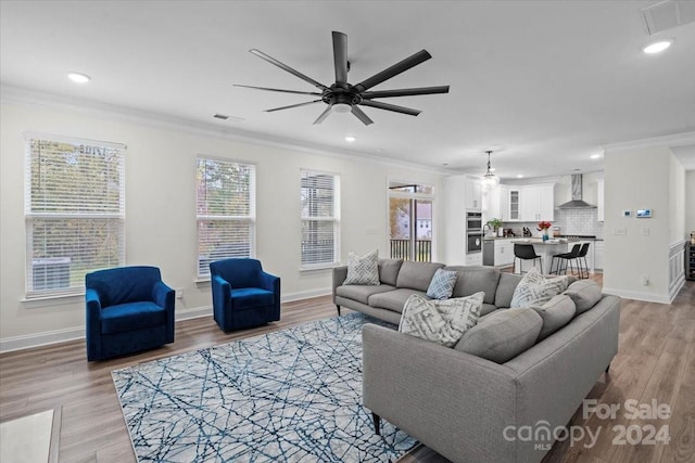 living room featuring light hardwood / wood-style floors, ceiling fan, and crown molding