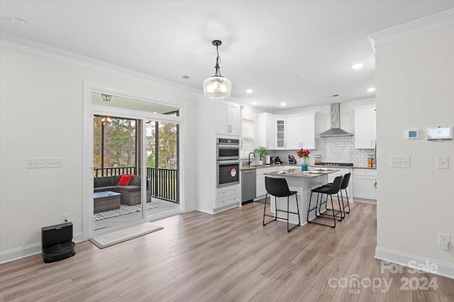 kitchen featuring light hardwood / wood-style floors, wall chimney range hood, white cabinetry, and appliances with stainless steel finishes