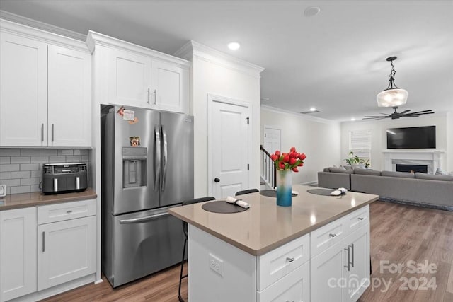 kitchen with tasteful backsplash, crown molding, white cabinetry, light wood-type flooring, and stainless steel refrigerator with ice dispenser