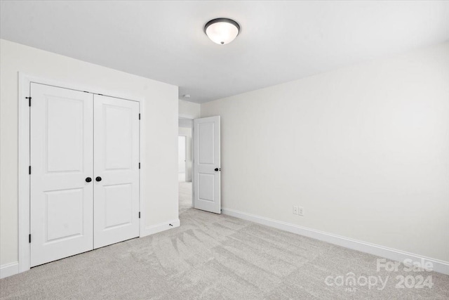 unfurnished bedroom with a closet and light colored carpet