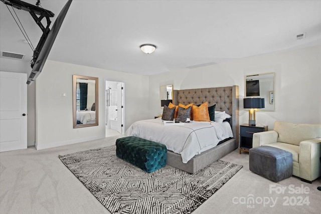 bedroom with light colored carpet and ensuite bath