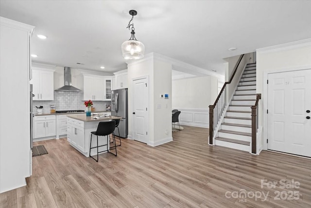 122 W Heart Pine Ln, Statesville, NC 28677 - kitchen featuring wall chimney exhaust hood, appliances with stainless steel finishes, a kitchen bar, a center island, and white cabinets