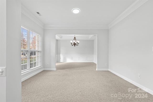 spare room with carpet floors, a chandelier, and ornamental molding