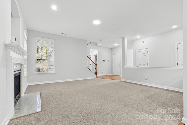 unfurnished living room with light colored carpet and a fireplace