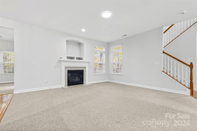 unfurnished living room with carpet and plenty of natural light