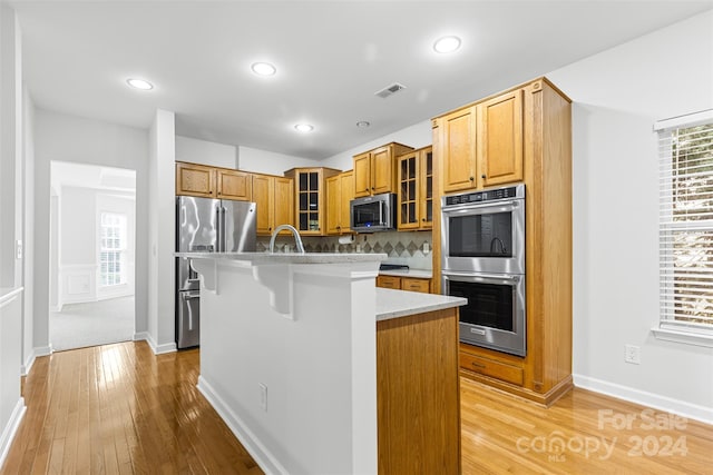 kitchen featuring a kitchen breakfast bar, a healthy amount of sunlight, a kitchen island with sink, and stainless steel appliances