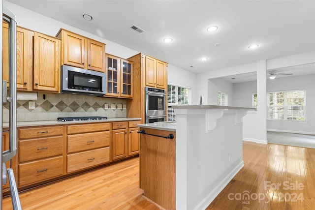 kitchen featuring light hardwood / wood-style flooring, a kitchen island, plenty of natural light, and appliances with stainless steel finishes