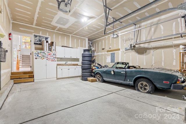 garage with electric panel, sink, and a garage door opener