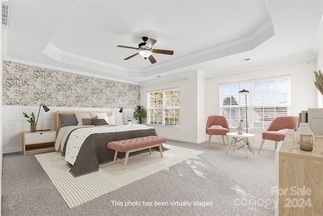 carpeted bedroom with ceiling fan, crown molding, multiple windows, and a tray ceiling