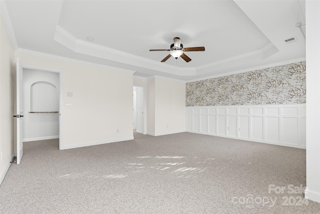 spare room featuring carpet flooring, a raised ceiling, and ceiling fan