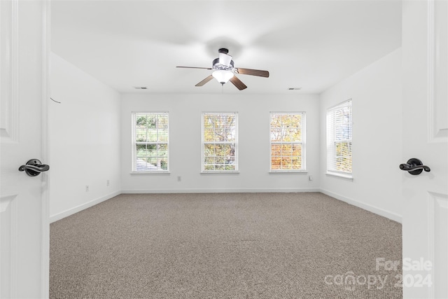 empty room featuring ceiling fan, carpet floors, and a healthy amount of sunlight