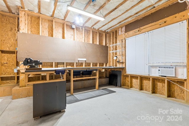 miscellaneous room with concrete flooring, a workshop area, and cooling unit