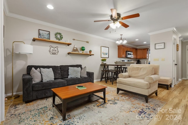 living room featuring ceiling fan with notable chandelier, crown molding, and light hardwood / wood-style flooring