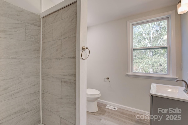 full bath featuring vanity, wood finished floors, baseboards, visible vents, and toilet