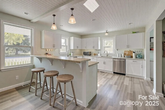 kitchen with a sink, white cabinets, a kitchen breakfast bar, and stainless steel dishwasher