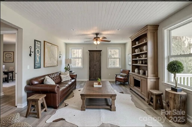 living room featuring baseboards, light wood-style flooring, wood ceiling, and ceiling fan