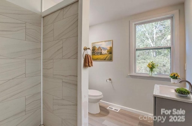 full bathroom with visible vents, baseboards, toilet, wood finished floors, and vanity