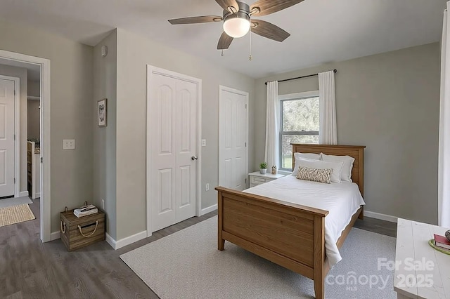 bedroom with dark wood finished floors, baseboards, and multiple closets