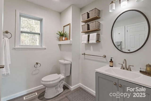 bathroom with vanity, wood finished floors, visible vents, baseboards, and toilet