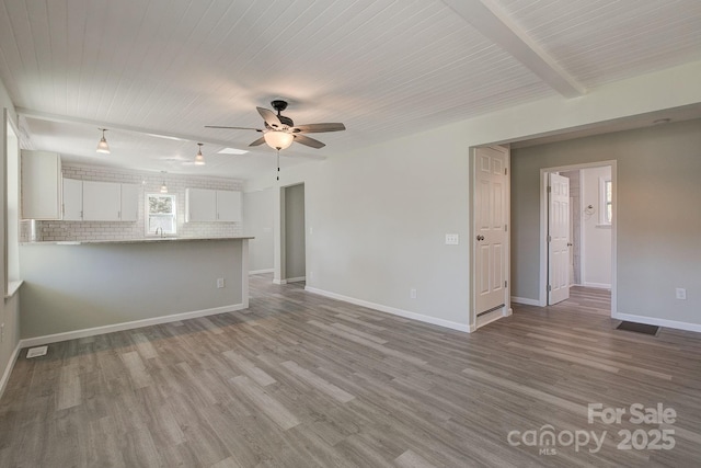 unfurnished living room with visible vents, wood finished floors, baseboards, and ceiling fan